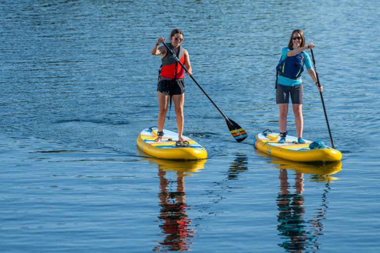 SUP Basics – Smiling paddlers practicing stance and paddle control on calm water