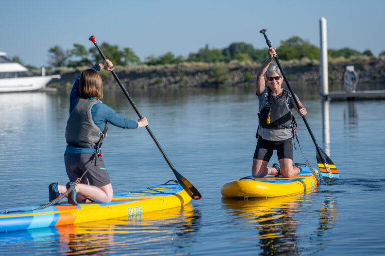 Instructor guiding first-time paddleboarders during a SUP Basics lesson at Columbia Point Marina